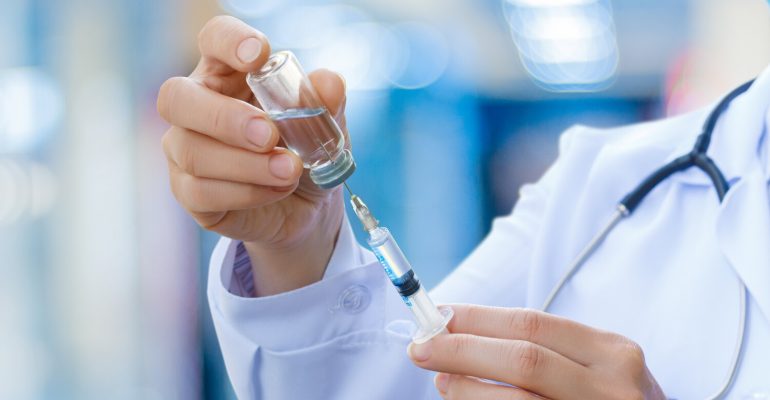 The doctor prepares the syringe for vaccination.